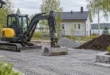 Maanrakennusliike: pieni telakaivinkone ja erilliset maa-aineskasat omakotitalon pihatyömaalla
